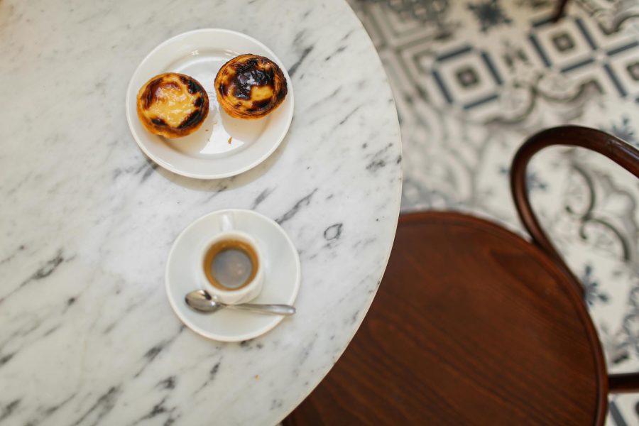 Uma mesa com café e 2 pasteis de nata. 